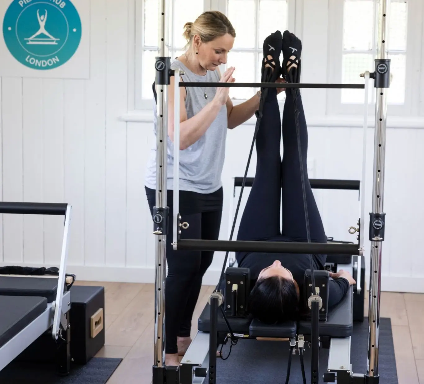 A teacher guiding a client with legs raised on the tower