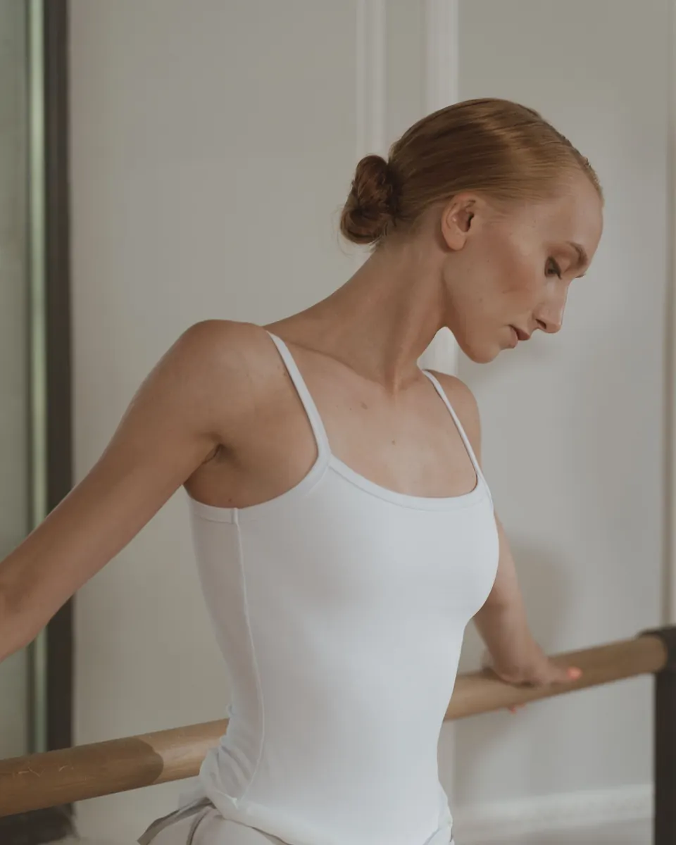 A woman holding a ballet barre in a quiet studio