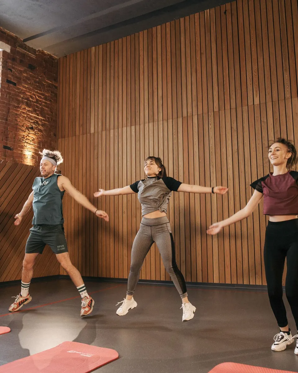 A group doing jumping jacks in a timber-walled studio